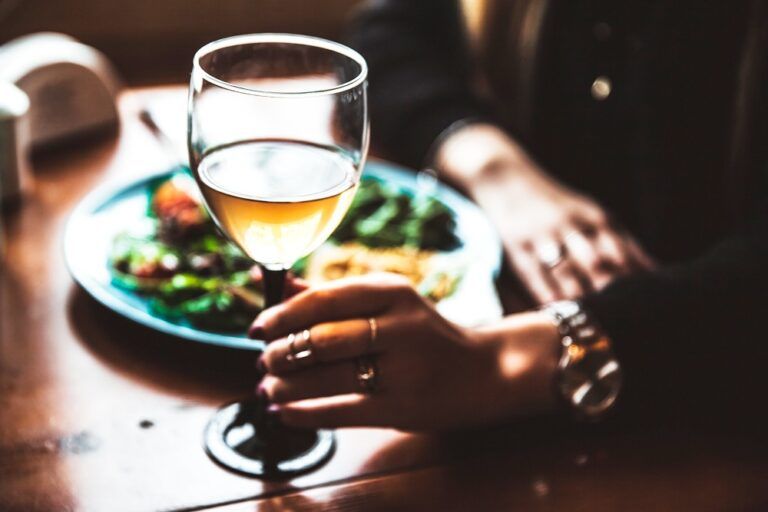 Mulher tomando vinho e almoçando