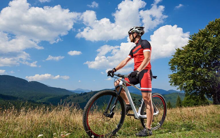 Ciclista praticando o cicloturismo, parando para apreciar uma paisagem