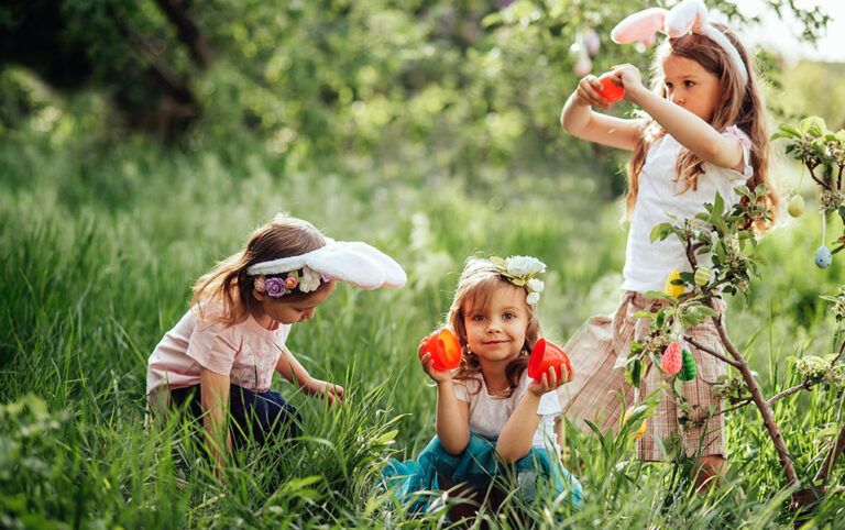 Três crianças usando tiara com orelhas de coelho e flores se divertindo em uma viagem de Pascoa